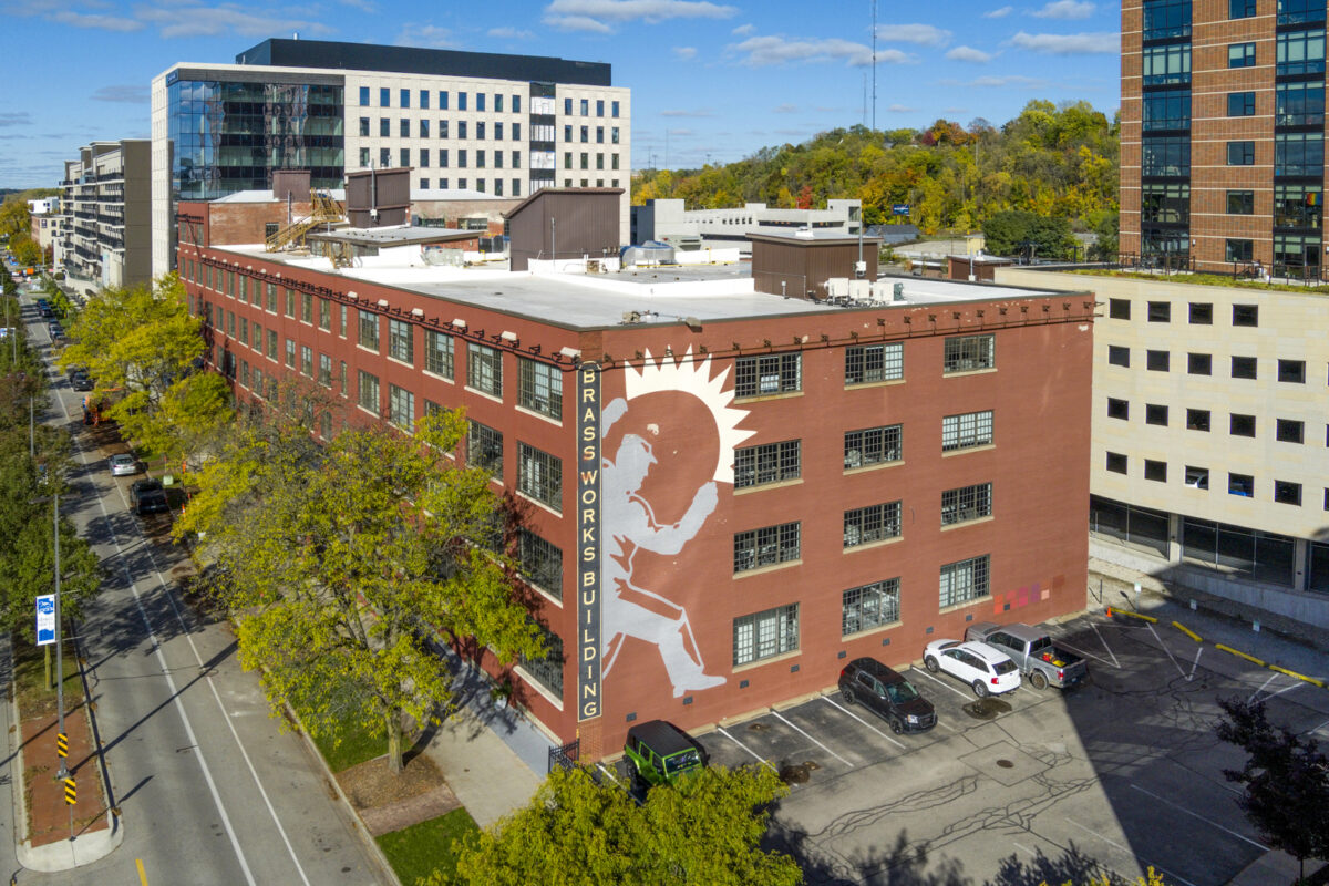 The exterior of the Corewell Brassworks building features a mural and brick exterior.