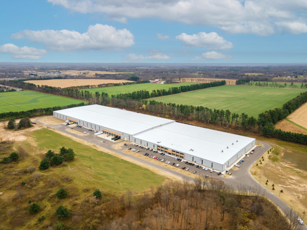 An aerial view of a large warehouse building surrounded by green fields.