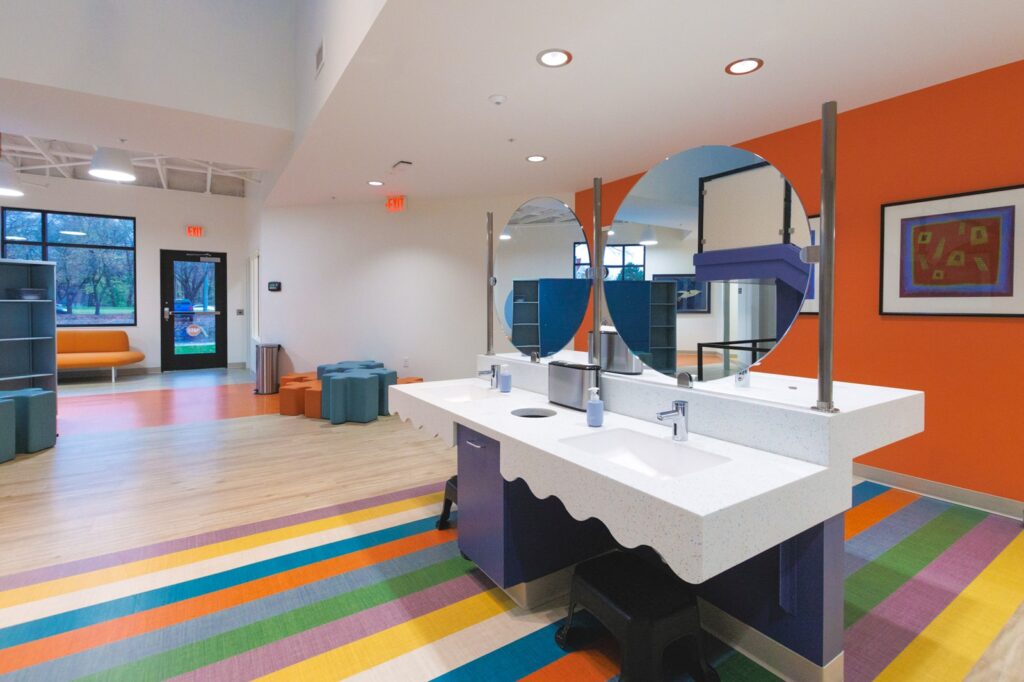 Large open room with colorful flooring, two sinks, and mirrors
