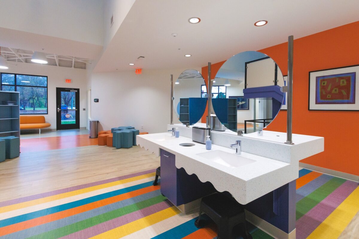 Large open room with colorful flooring, two sinks, and mirrors
