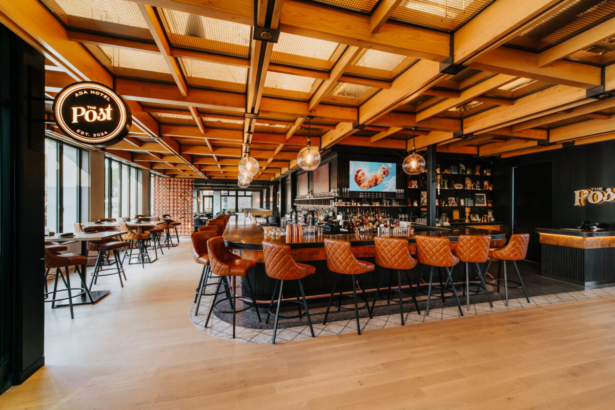 Main area in Ada hotel with seating, large windows and overhead lighting