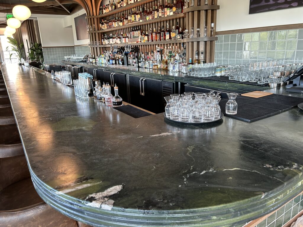 Rix bar at Ada Hotel with curved wood counter and drinks and bottles behind the bar.